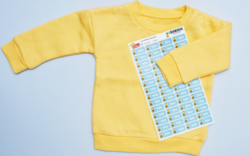 Um jumper amarelo com uma folha de etiquetas My Nametags em um fundo azul claro