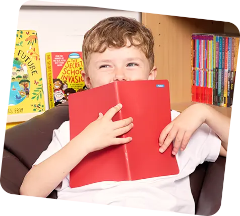 garotinho segurando um caderno vermelho na frente do rosto